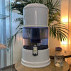 Aqualine 12 Waterfilter ABS – mineraalrijk en vitaliserend waterfilter in sfeervolle setting op tafel met glas drinkwater.