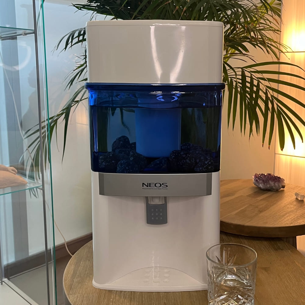 Aqualine NEOS Waterfilter Glas – mineraalrijk en vitaliserend waterfilter in sfeervolle setting op tafel met glas drinkwater.